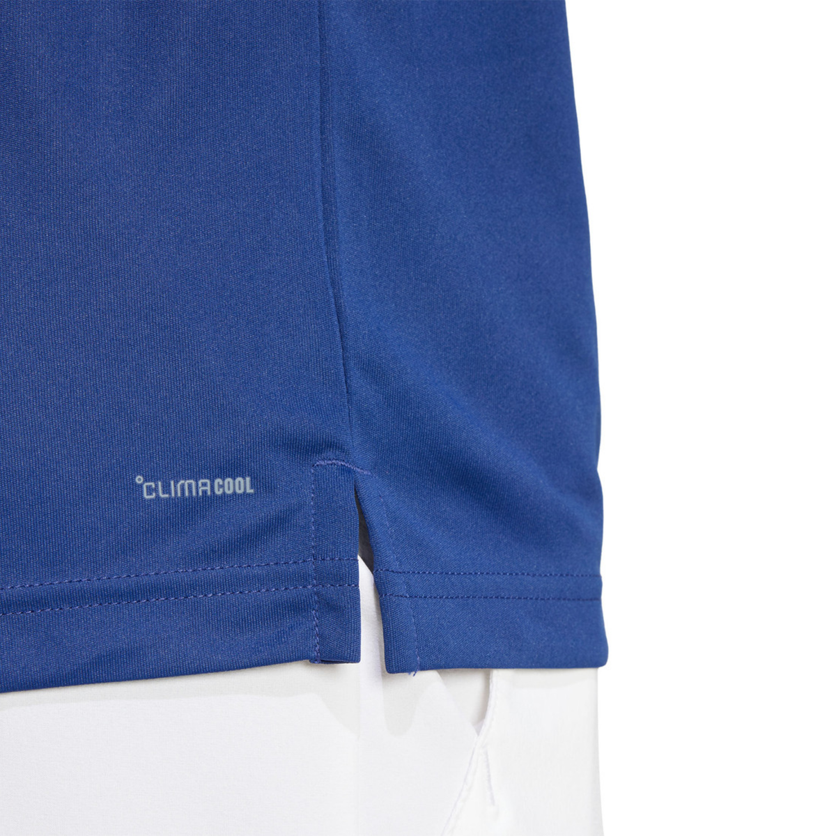 Close-up of the lower hem and side slit of the blue Adidas polo shirt.