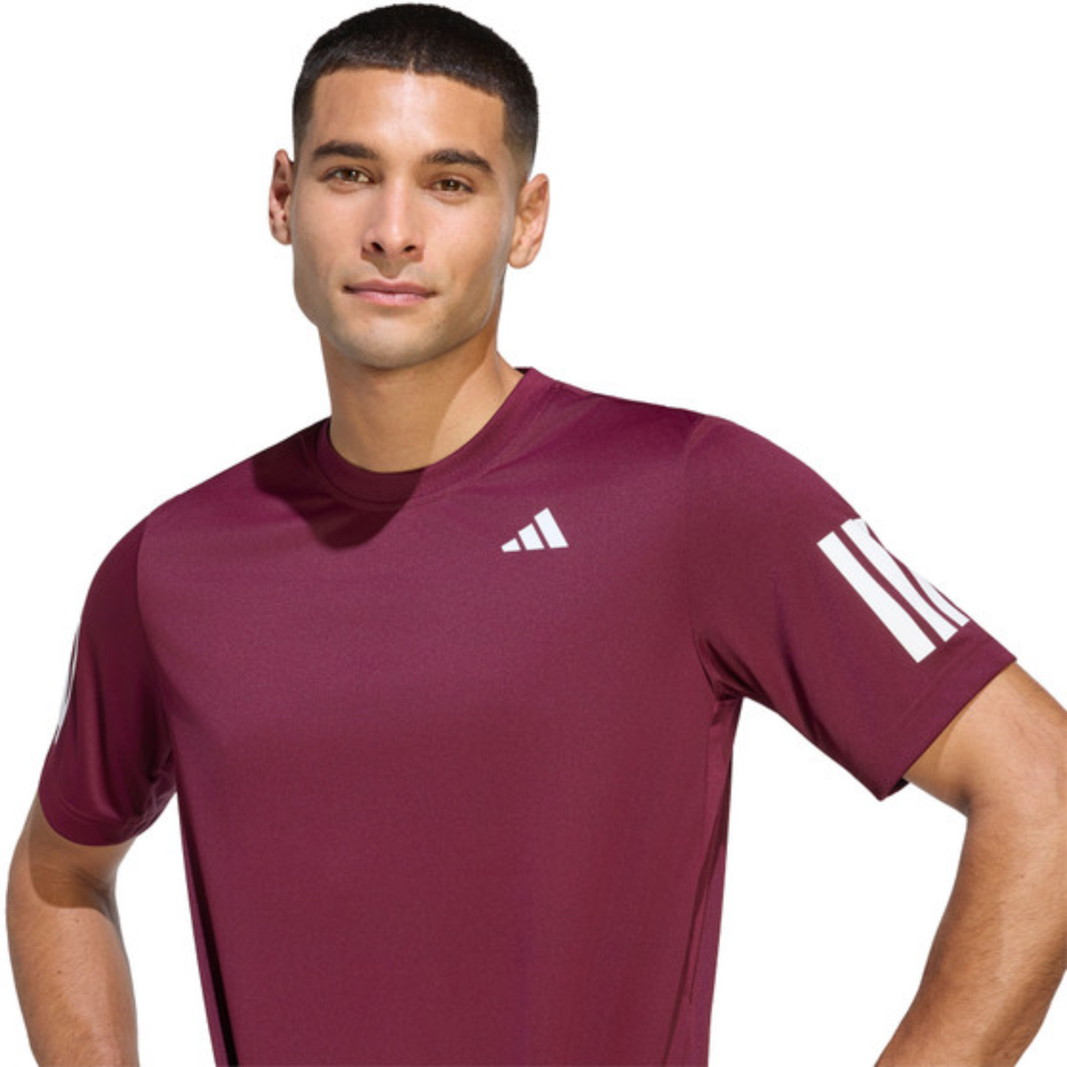 Front view of a model wearing the burgundy adidas T-shirt with hands on hips.