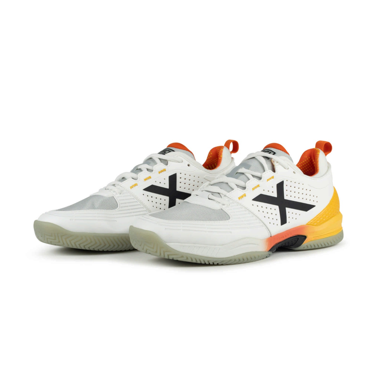 Pair of Munich Atomik 55 white padel shoes shown from a front angled view, highlighting the black X logos, white laces, light grey mesh toe panels, bright yellow heel supports, orange lining and translucent pale outsoles.