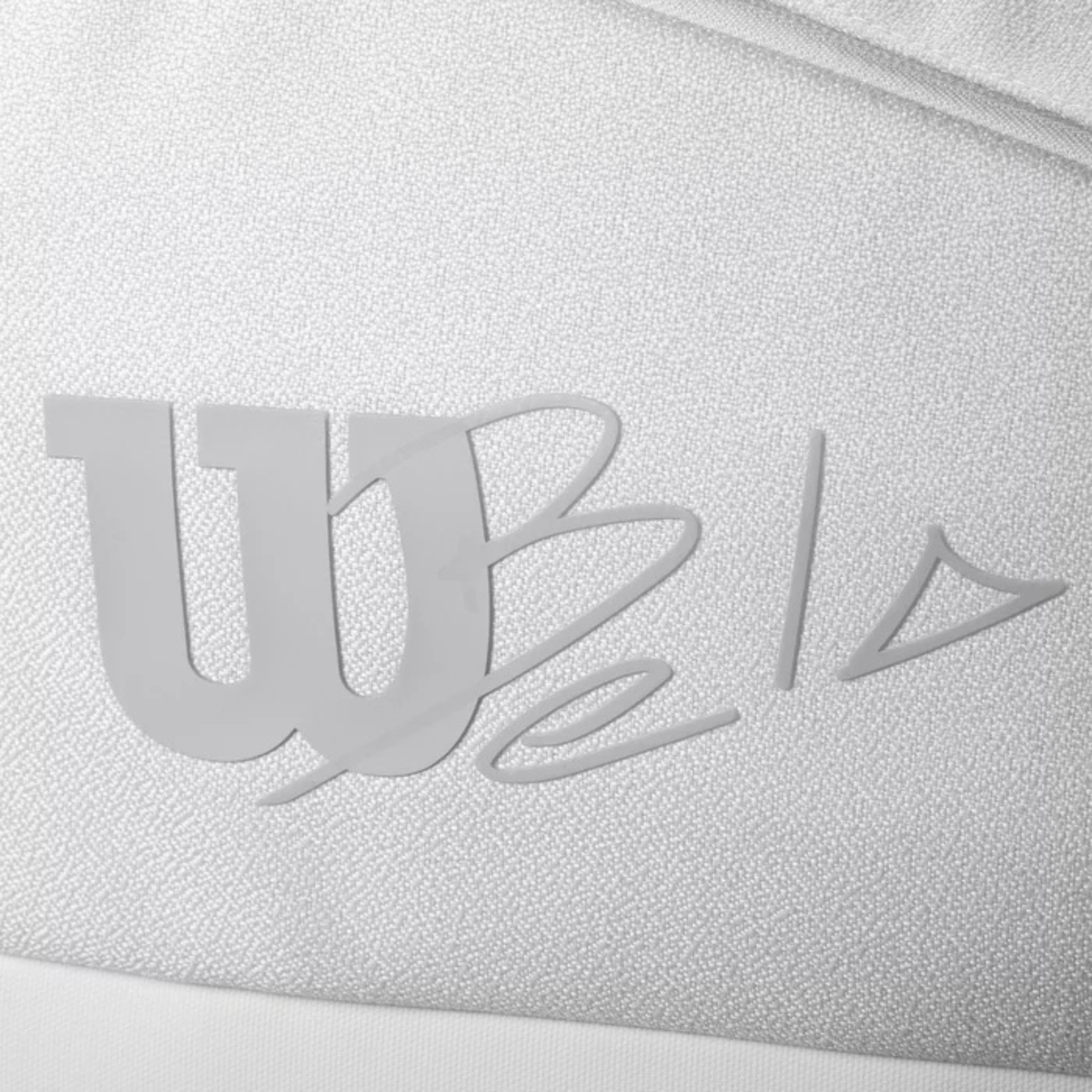 Close-up of the Bela logo printed on the textured white fabric of the Wilson padel bag.