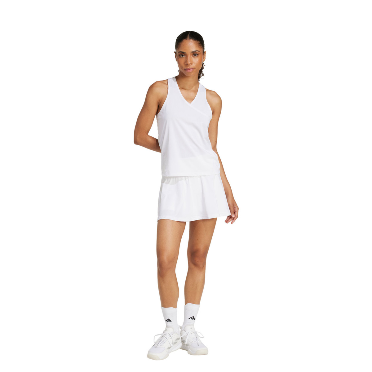 Full-body view of a female model wearing the adidas Club Climacool Skirt White with a white sleeveless top, white socks and white Adidas tennis shoes.