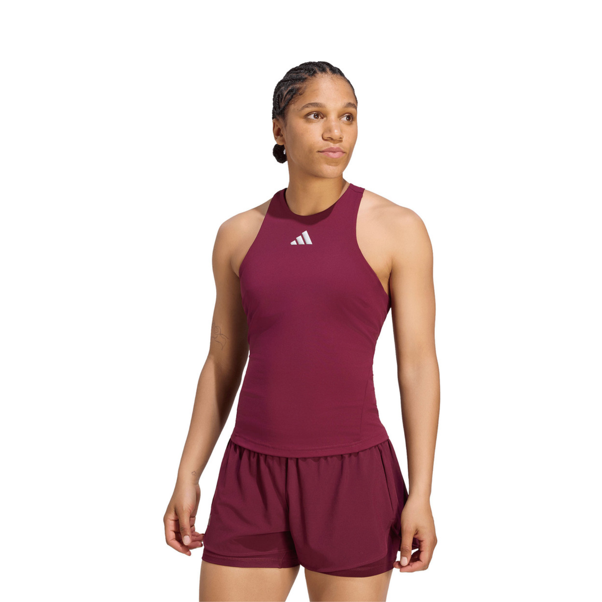 Front view of a female model wearing the adidas Silver Y-Tank in burgundy, paired with matching adidas shorts.