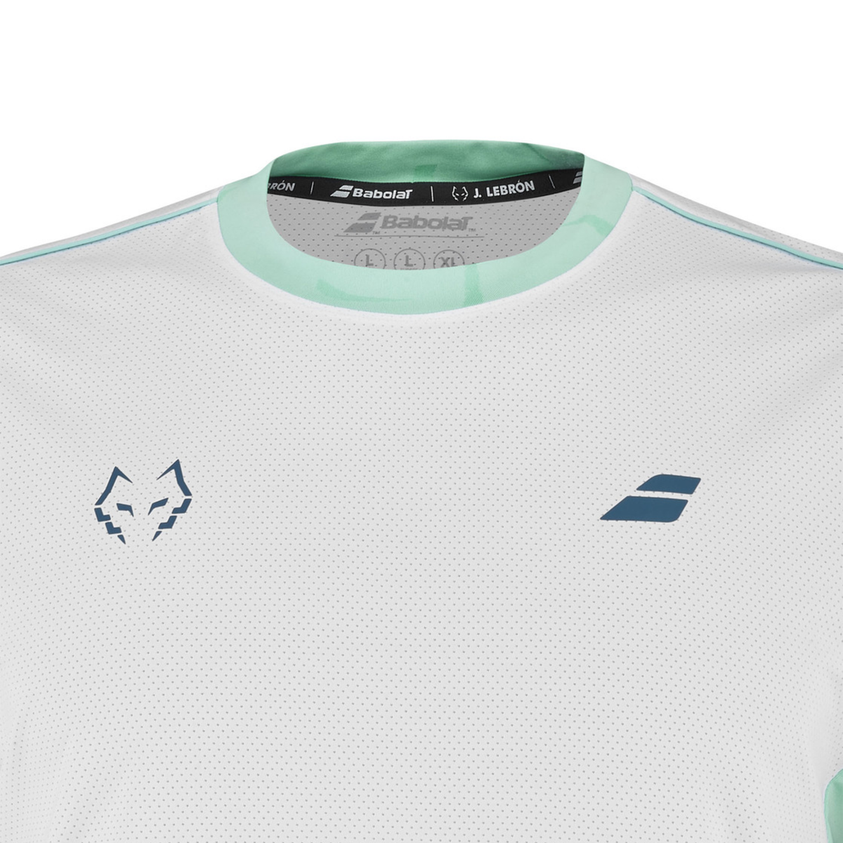 Close-up of the upper front of the Babolat Crew Neck Tee Lebron Men White 2027, showing the light turquoise crew neck collar, textured white fabric and dark blue Babolat and Juan Lebron chest logos.