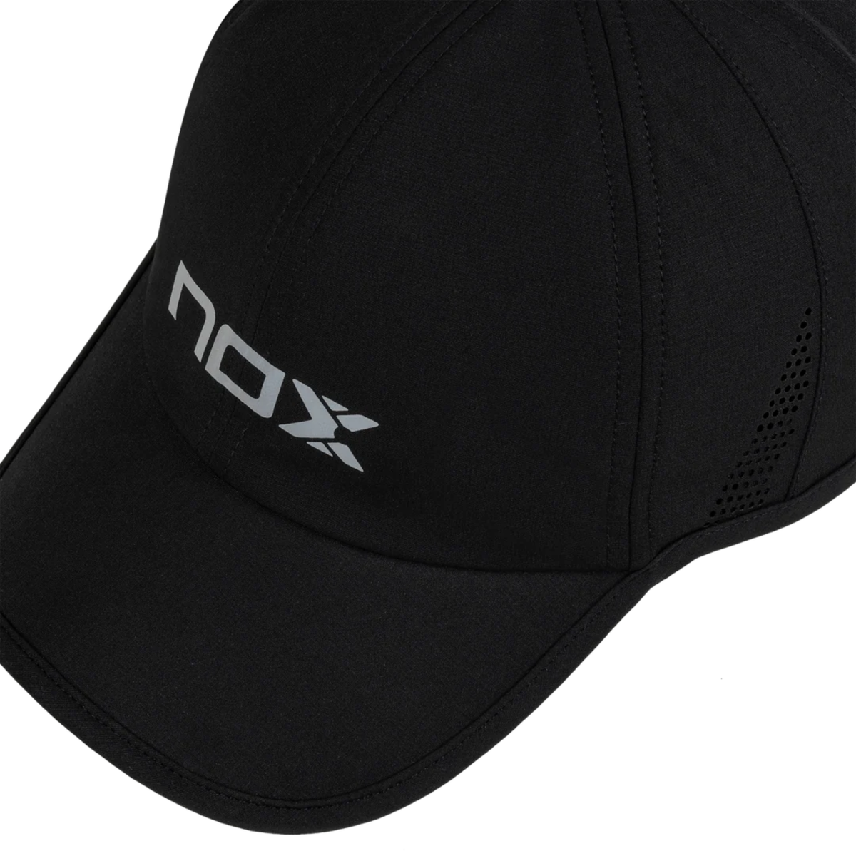 Close-up detail of the Nox Black/White Cap, highlighting the grey front logo, black fabric, curved visor stitching and perforated side ventilation holes.