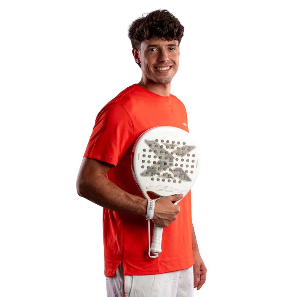 Male padel player wearing a red sports shirt and white shorts while holding the NOX Genius 12K Alum Xtrem Lite Agustín Tapia 2027 padel racket in front of him.