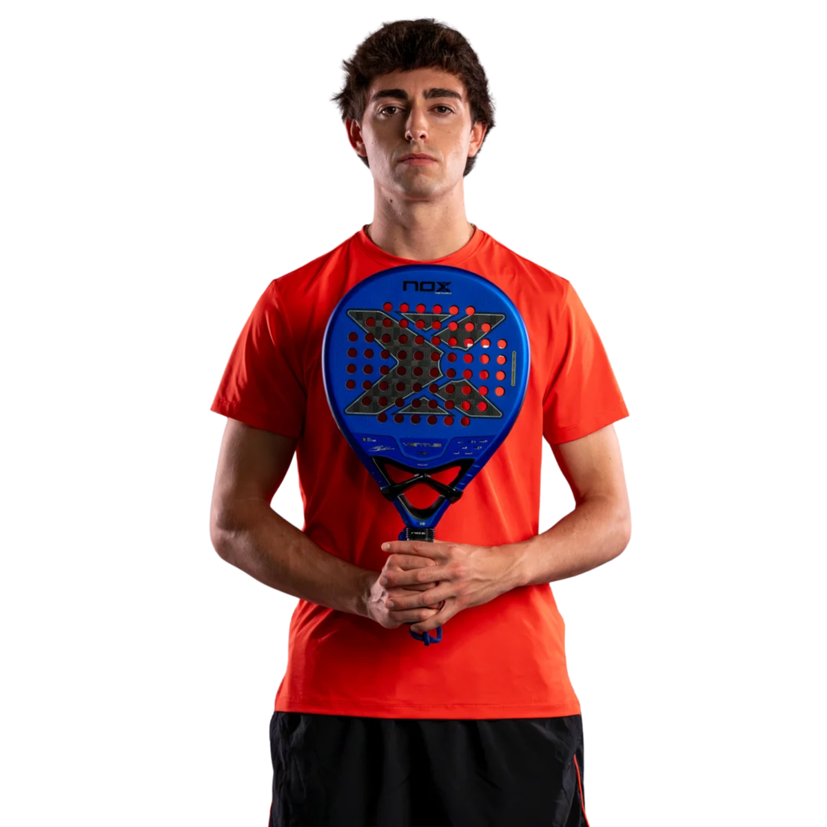 Male padel player wearing a red sports shirt while holding the NOX Ventus Hybrid 12K Xtrem Edu Alonso 2027 padel racket in front of him.
